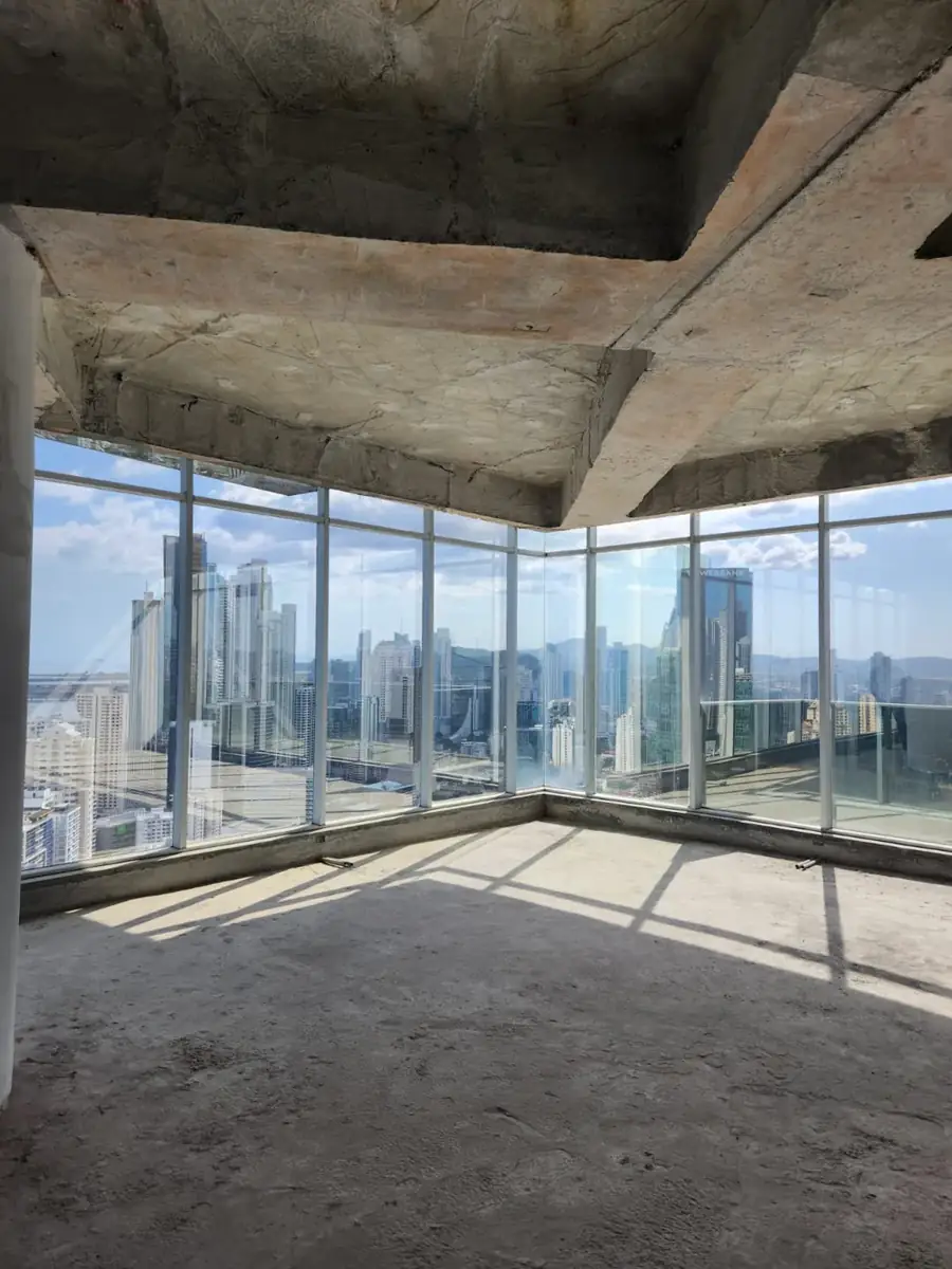 Obra civil: esquina de un piso en construcción con ventanales y vista a la ciudad